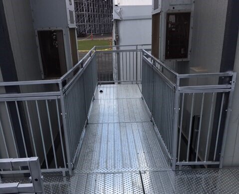 A walkway with metal railing and steps leading to the top floor.