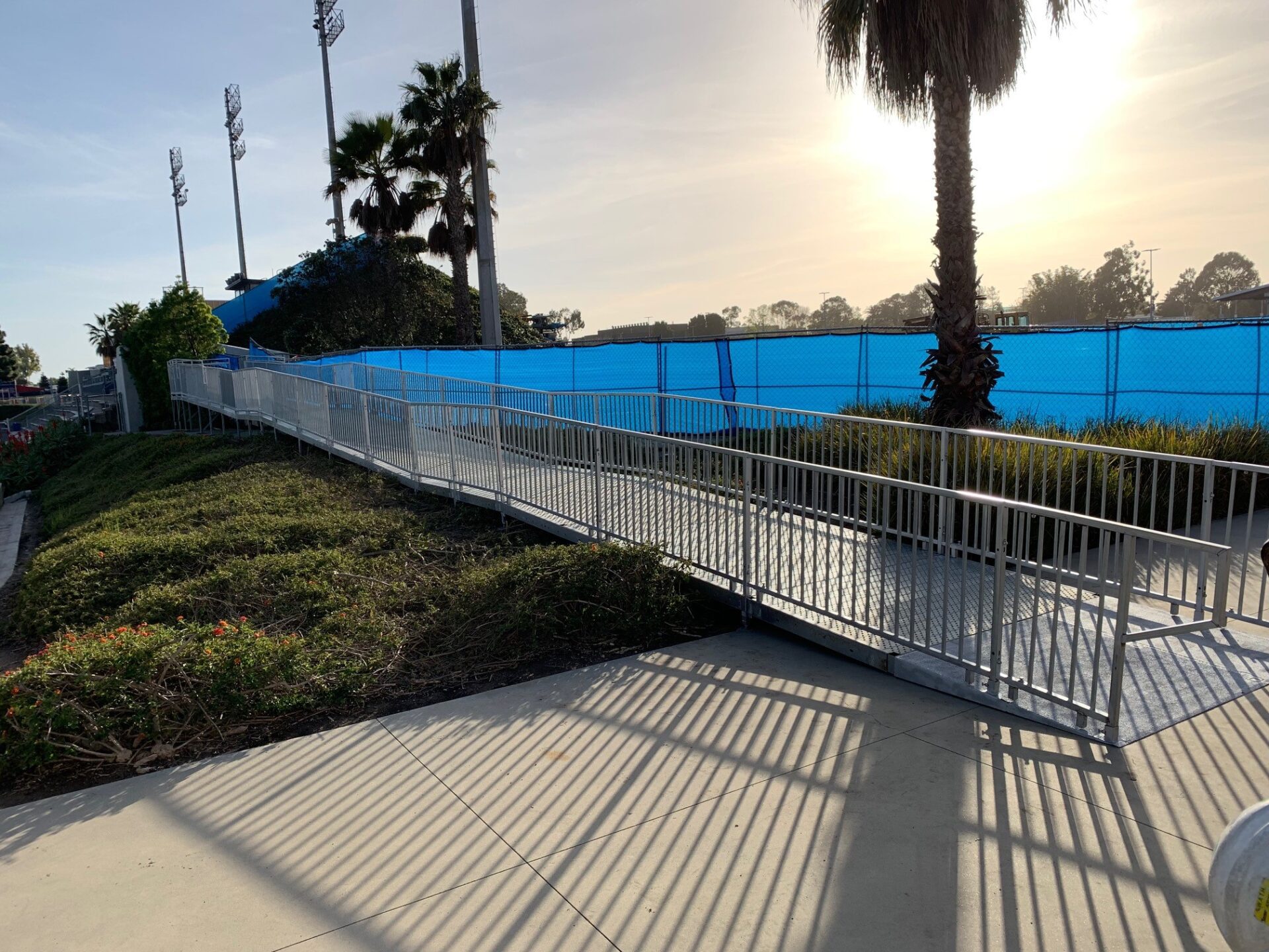 A walkway with metal railing and blue fence.